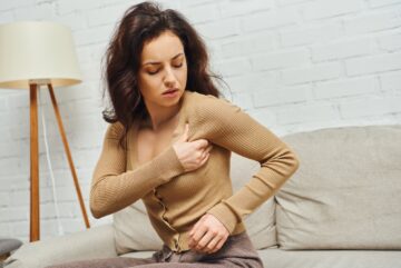 Brunette woman in casual brown jumper massaging lymphatic nodes on armpit while doing drainage