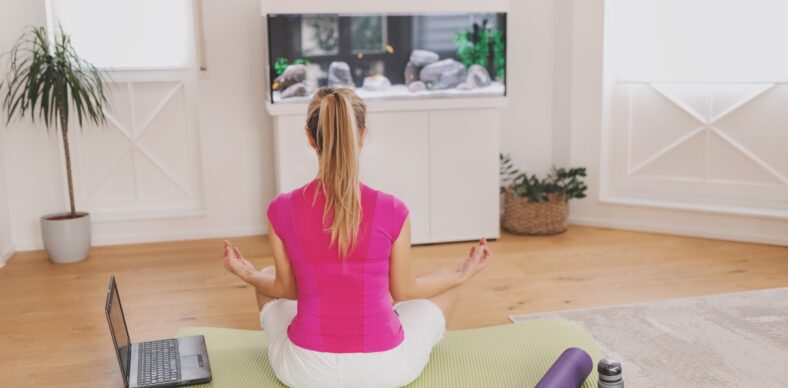 Girl doing yoga with roller at home in front of aquarium